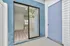 Inviting apartment entrance with modern sliding glass door opening to bright, spacious interior featuring elegant wood flooring.