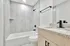 Elegant bathroom with modern fixtures, featuring a sleek granite countertop, spacious tub, and stylish matte black accents.