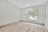 Bright and spacious room with sleek wood flooring and large window overlooking greenery.