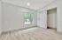 Bright, airy bedroom with elegant wood flooring and a large window offering natural light. Features a spacious closet with sliding doors.