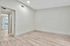Bright and modern room with sleek wood flooring, fresh light walls, and ample natural light from a large window.