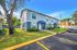 Charming duplex with blue awnings, manicured lawns, and ample parking nestled in a serene neighborhood.