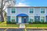 Charming two-story blue townhouse with lush landscaping, featuring large windows and an inviting entrance.