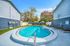 Inviting outdoor pool area with lounge chairs, surrounded by lush greenery and patio umbrellas, perfect for relaxation and enjoyment.