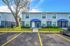 Charming two-story townhouse with modern blue exterior, featuring dual entrances and lush green surroundings.