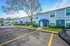 Charming apartment building with blue awnings and lush greenery, featuring ample parking on a sunny day.