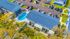 Aerial view of a charming apartment complex featuring a sparkling pool, inviting patios, and ample parking with lush greenery.