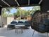 Inviting outdoor patio featuring cozy wicker seating, a stylish egg chair, and relaxing garden views.