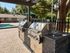 Inviting outdoor area featuring sleek stainless steel grills and a shimmering swimming pool, set against a backdrop of lush greenery for perfect summer gatherings.