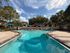 Inviting outdoor swimming pool with vibrant lounge chairs and umbrellas, surrounded by lush greenery and a serene atmosphere.