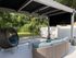 Charming outdoor patio with comfortable rattan seating, lush greenery, and a stylish pergola for relaxation.