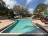 Inviting outdoor pool surrounded by colorful lounge chairs, perfect for relaxation under sunny skies and lush greenery.