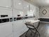 Modern laundry room with efficient stacked washers and dryers, complemented by a stylish laundry cart on sleek wooden flooring.