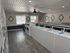 Modern laundry room with sleek countertop, stainless steel sink, ample washers and dryers, and stylish ceiling fan.
