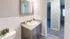 Chic bathroom with modern vanity, elegant mirror, and ambient lighting, leading to bright and spacious living area.