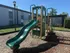 Inviting outdoor playground with a vibrant green slide and climbing area, perfect for children's play in a sunny apartment community.