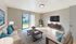 Bright and inviting living room featuring contemporary furniture, a large wall-mounted TV, and a sliding glass door opening to a lush green backyard.