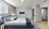 Elegant bedroom featuring a plush blue bed, modern decor, sleek flooring, and ample closet space with contemporary furnishings.