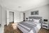 Elegant bedroom featuring a plush gray tufted headboard, modern decor, and abundant natural light highlighting the stylish wood floors.