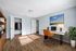 Bright and inviting home office with modern desk, orange chair, vibrant artwork, and wooden floors.