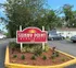Inviting entrance to Sunny Point Apartments with vibrant landscaping and ample parking space.