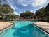 Inviting swimming pool area with vibrant lounge chairs and umbrellas, surrounded by lush greenery, ideal for relaxation and leisure.