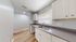 Elegant kitchen with modern gray countertops, sleek white cabinets, and warm wood flooring, offering ample natural light.