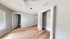 Bright and airy bedroom with sleek hardwood floors, open closet, and large window for natural light.