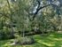 Enchanting backyard view featuring lush green grass, vibrant trees, and a charming iron fence, offering a serene oasis.