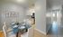 Modern dining area with a sleek glass table, elegant white chairs, and a cozy kitchen, perfect for stylish entertaining.