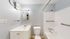 Bright, modern bathroom with sleek fixtures, ample lighting, and a stylish white vanity.