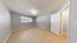 Bright and spacious bedroom with large window, light gray walls, and elegant tile flooring.