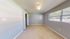 Bright and airy bedroom with neutral tones, large window for natural light, and modern tile flooring.