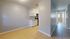 Bright kitchen area with sleek white cabinets, modern appliances, and inviting tiled flooring, leading towards sunlit corridors.