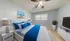 Inviting bedroom with elegant white and blue bedding, soft lighting, and a modern decor perfect for relaxation.