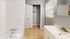 Bright and spacious bathroom featuring a pristine white bathtub, elegant vanity, and convenient closet space.