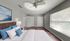 Bright and spacious bedroom featuring modern decor, large windows for natural light, and elegant ceiling fan.