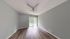 Bright, spacious room with elegant wood flooring, modern ceiling fan, and large glass doors opening to a serene outdoor view.