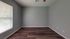 Bright, spacious room with modern gray walls and elegant wooden flooring, complemented by a large window for abundant natural light.