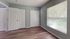 Bright room with large window, sleek wooden flooring, and ample closet space, ideal for a cozy bedroom or home office.