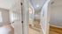 Inviting apartment hallway with stylish wood flooring, directing toward a bright living space and modern bathroom.