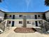 Charming modern apartment complex with vibrant blue doors, spacious balconies, and well-maintained landscaping under a clear blue sky.