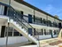 Bright and inviting two-story apartment building with modern railings, spacious balconies, and a sleek exterior under a clear blue sky.