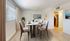 Chic dining area with a modern table set for four, featuring neutral tones, elegant decor, and abundant natural light.