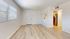 Bright and airy apartment with elegant wood flooring, large window with blinds, and modern stainless steel kitchen appliances.
