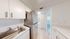 Modern kitchen with sleek stainless steel appliances, bright white cabinetry, and elegant wood flooring creating a fresh and inviting atmosphere.