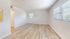 Bright, spacious room with elegant light wood flooring and large windows offering abundant natural light, ideal for versatile living or bedroom space.