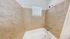 Bright bathroom featuring elegant beige tile walls, a clean white bathtub, and a modern shower fixture, perfect for relaxation.