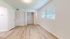Bright, airy room with elegant hardwood floors and a spacious closet, illuminated by abundant natural light through large windows.