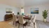 Sophisticated dining room featuring a polished wood table with elegant upholstered chairs, stylish artwork, and lush greenery creating a warm and inviting atmosphere.